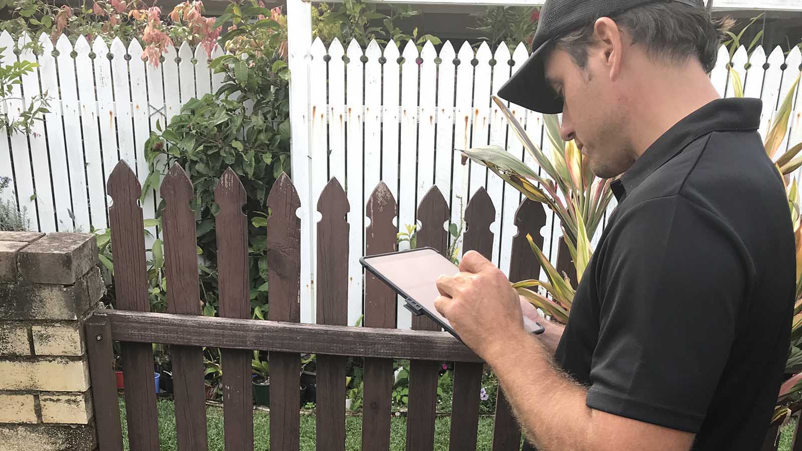 Building inspector in garden taking notes on an iPad.