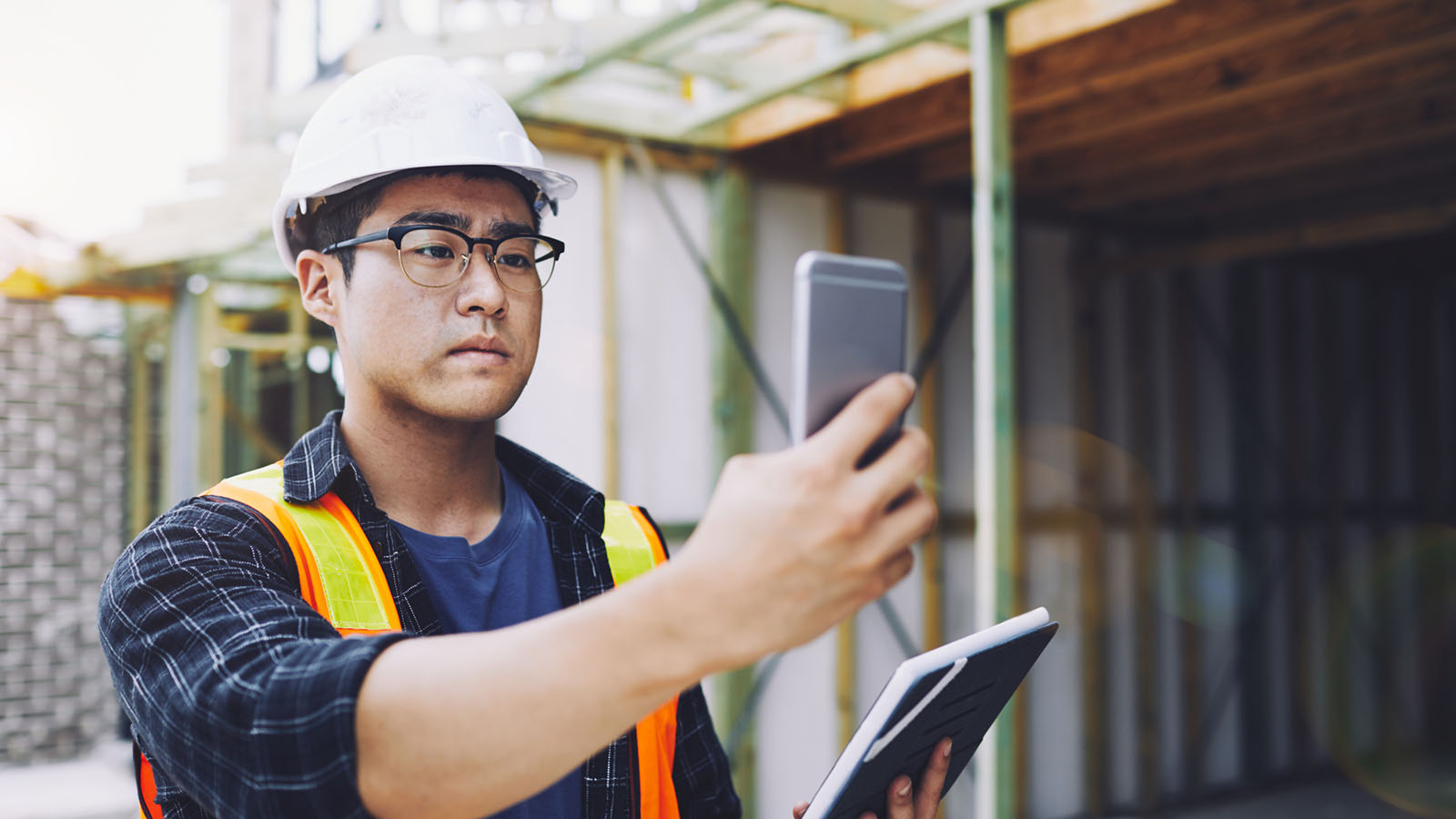 Building inspector using a phone to take photos of the construction process.