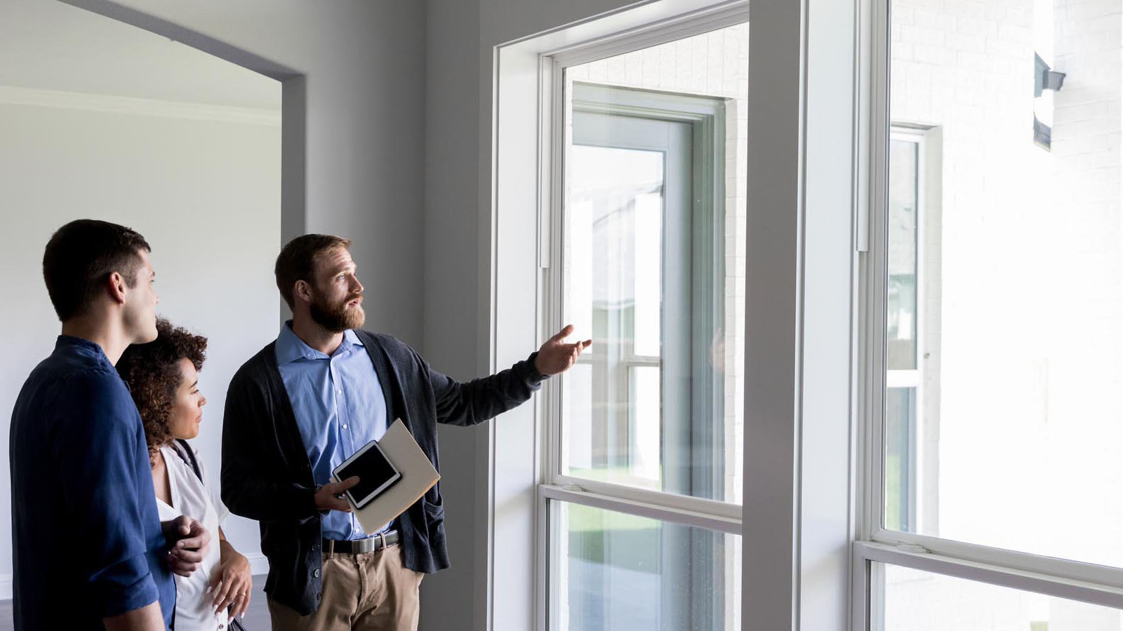 Homeowners looking at windows of a home with an inspector.