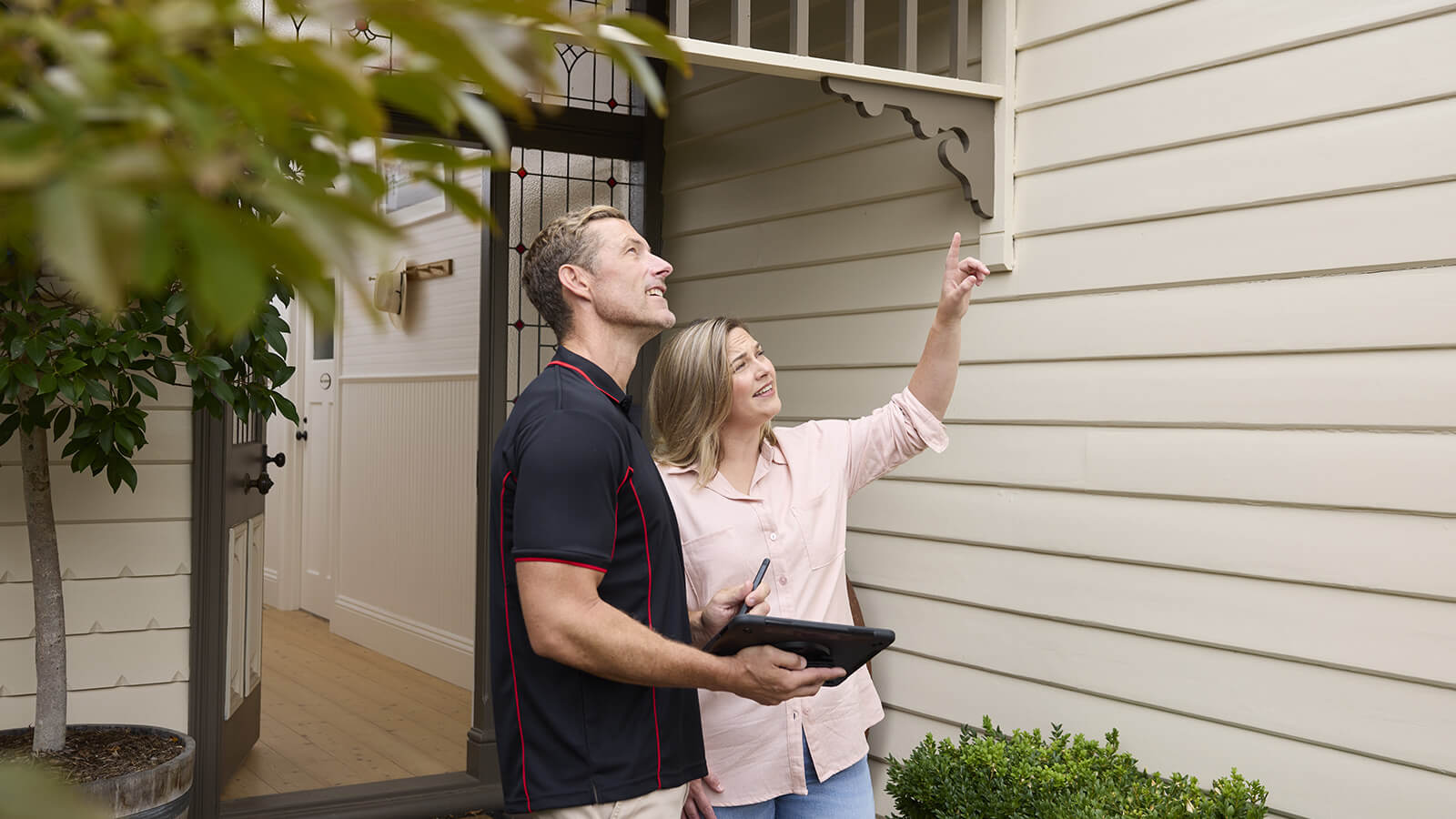 Building inspector and customer outside a home looking at the roof.