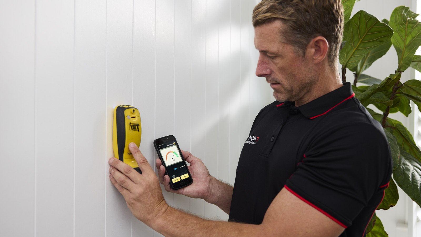 Building inspector using their phone and the Termatrac Sensor to check the interior of a house.