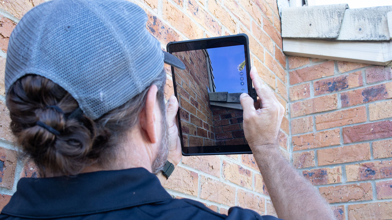 Building inspector using tablet to take photos of residential roof.