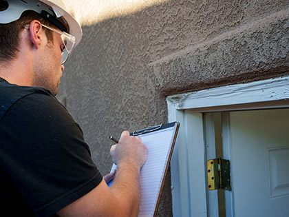 Building inspector inspecting a peeling, wooden door frame.