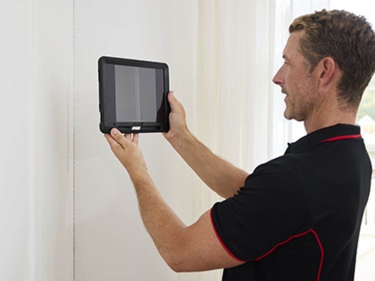 Building inspector holding a tablet up to a wall