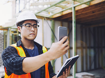 Building inspector using a phone to take photos of the construction process.