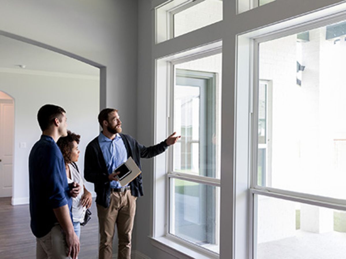 Homeowners looking at windows of a home with an inspector.