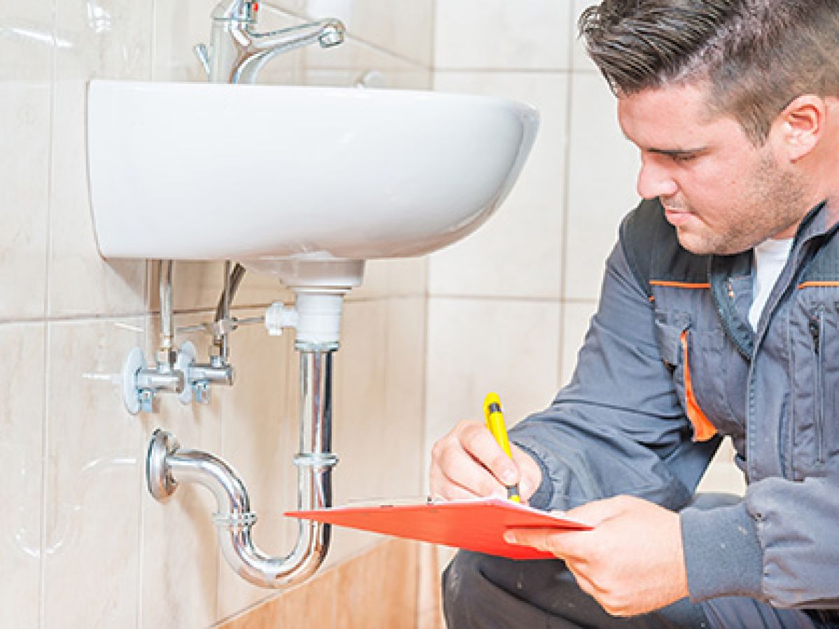 An inspector reviewing plumbing of a bathroom sink.