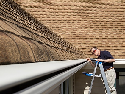 An inspector confirming a rain gutter meets specifications.