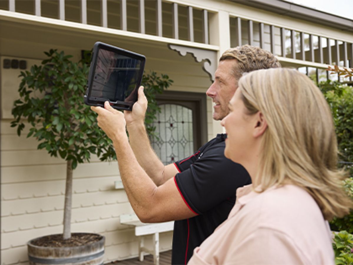 Building inspector taking photos of the exterior of a house, with the customer.