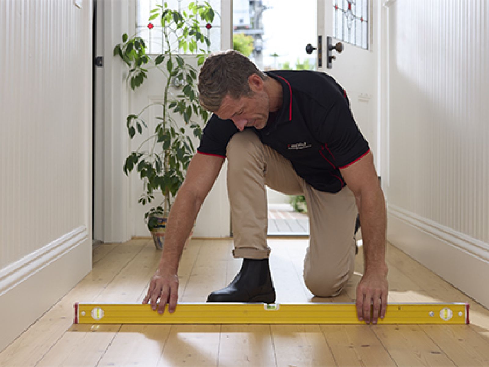 Building inspector kneeling down using a level to examine the floor.