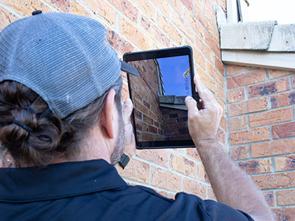 Building inspector using tablet to take photos of residential roof.