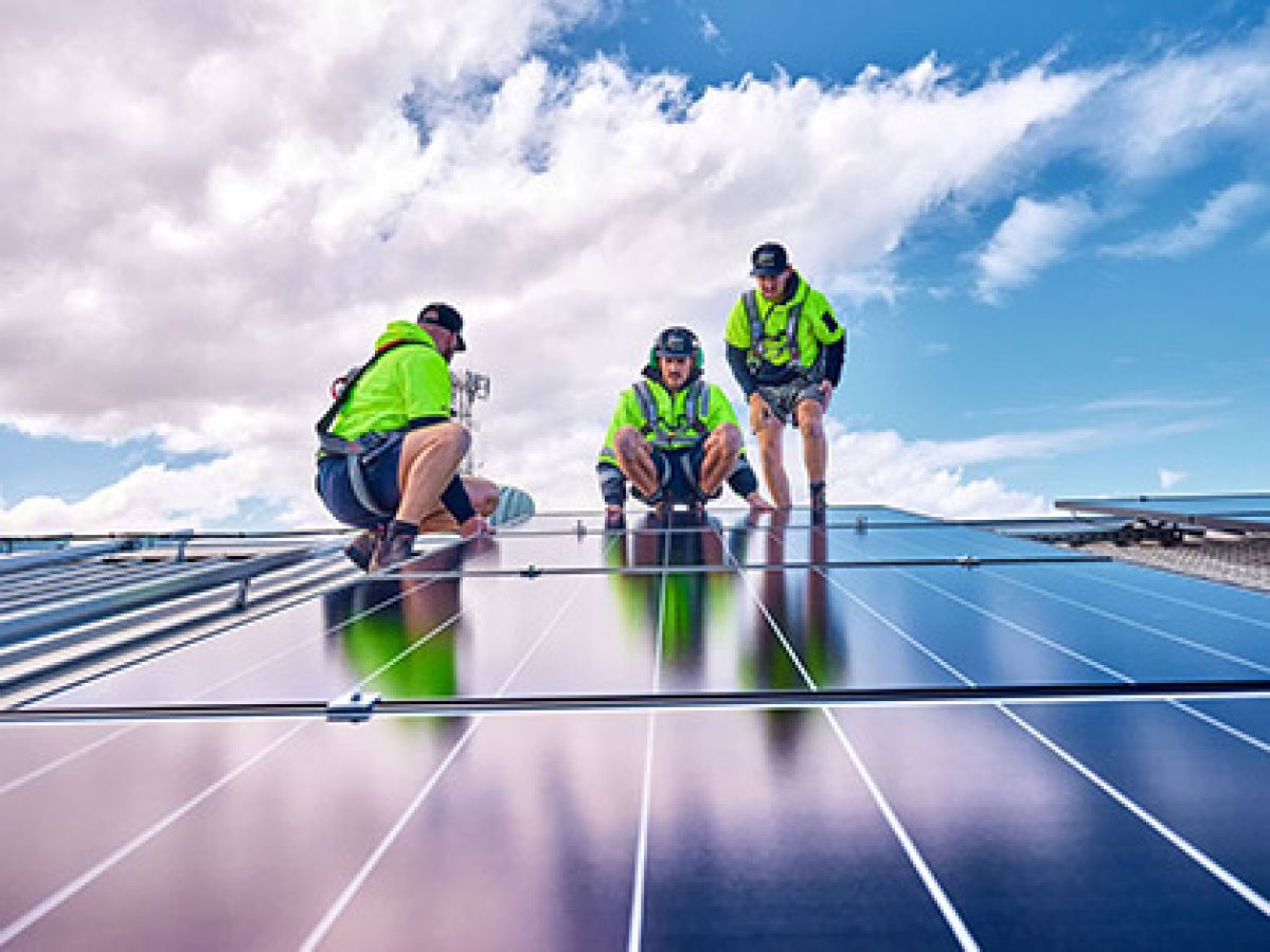 Solar installers on the roof laying a solar panel.