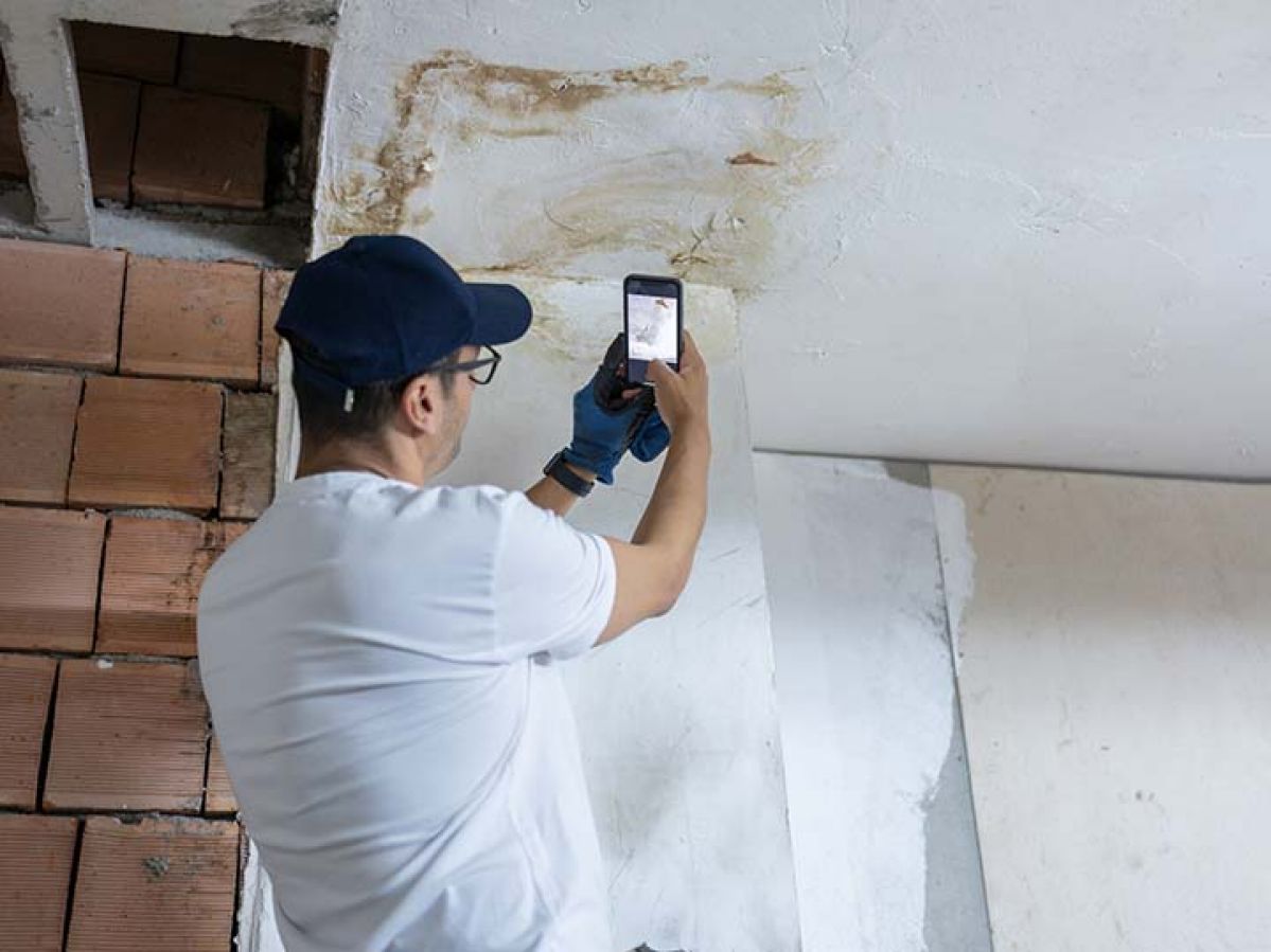 An inspector taking photos of a damaged roof.