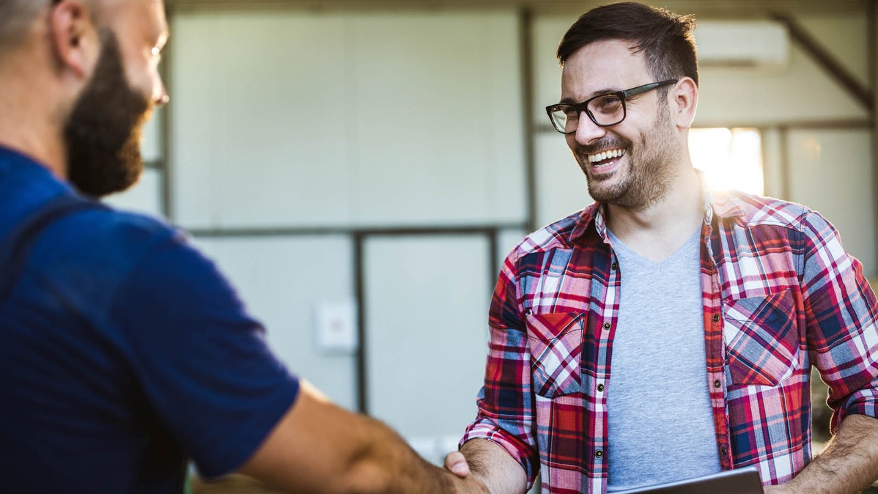 Two men shaking hands and smiling.