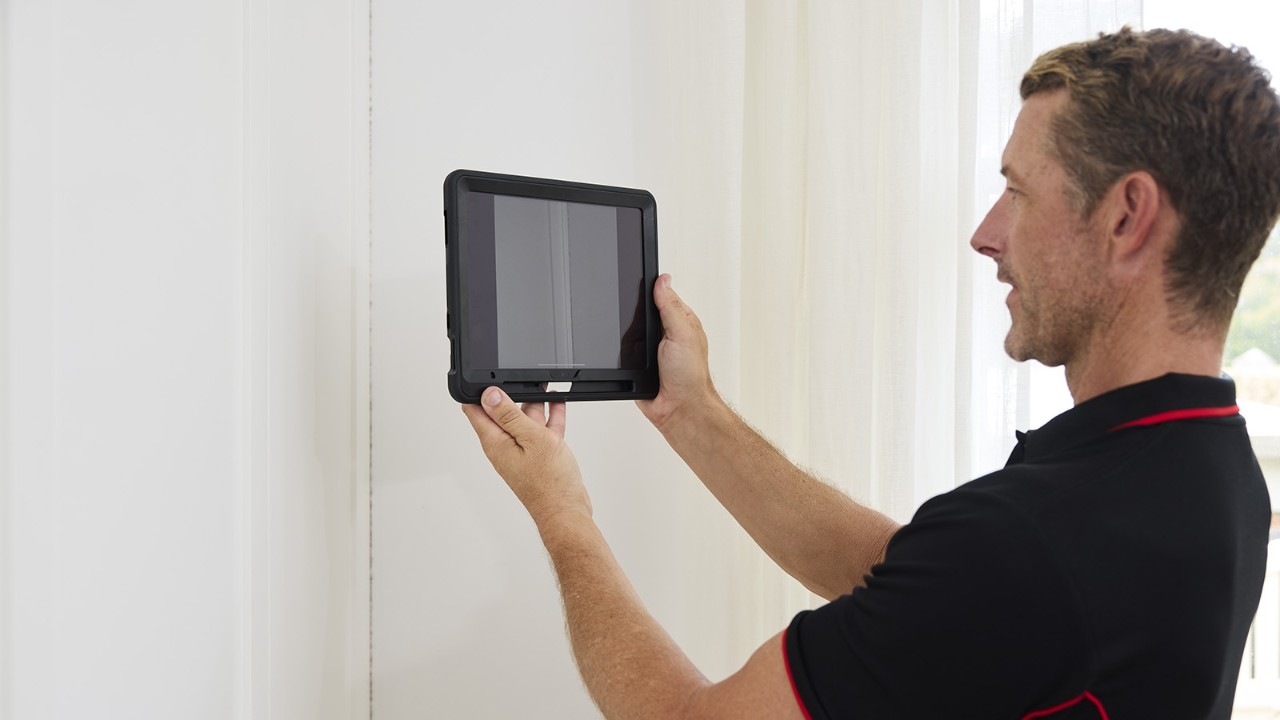 Building inspector holding a tablet up to a wall