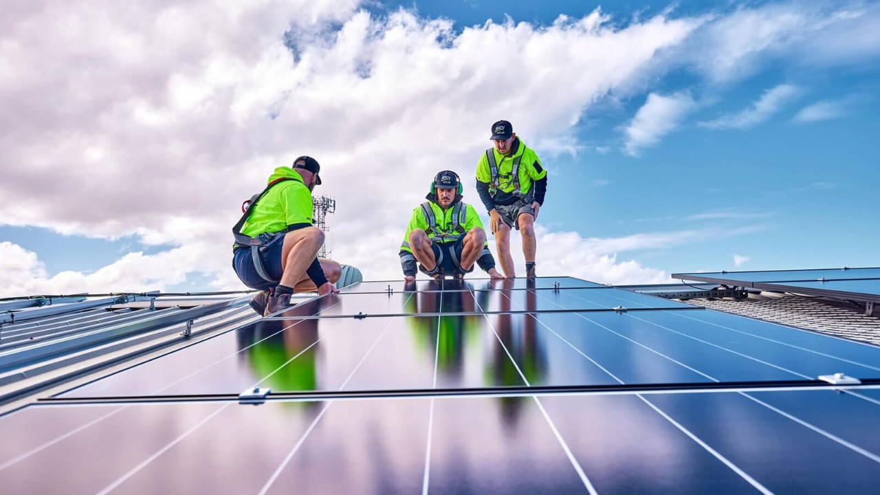 Solar installers on the roof laying a solar panel.